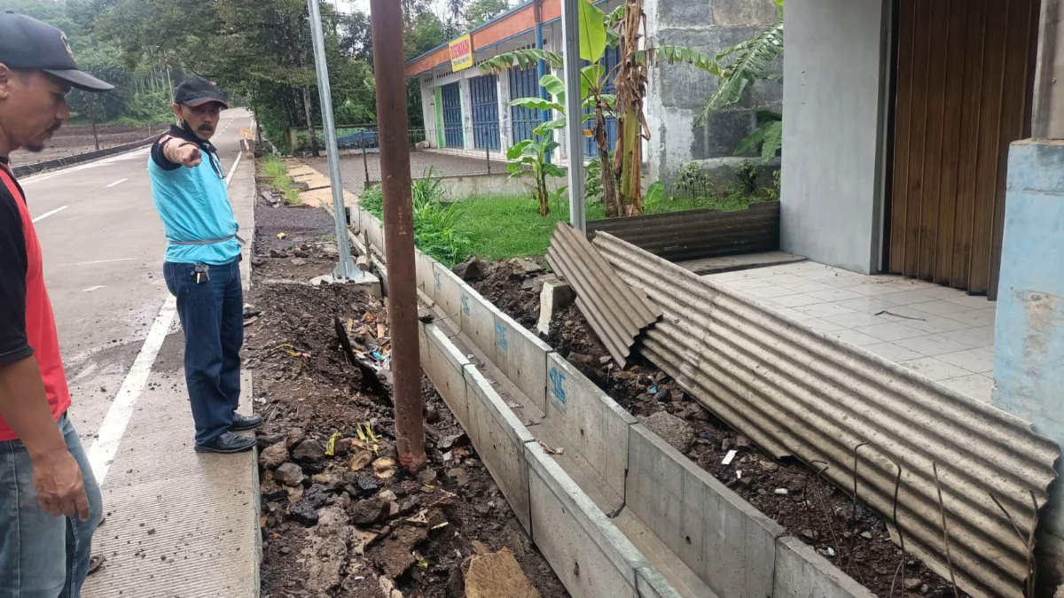 TUNJUKKAN: Kepala Desa Jambu Upriatna D beserta jajarannya menunjukkan saluran air yang tertutup drainase sehingga menyebabkan banjir di depan Kantor Desa Jambu Kecamatan Conggeang, kemarin.