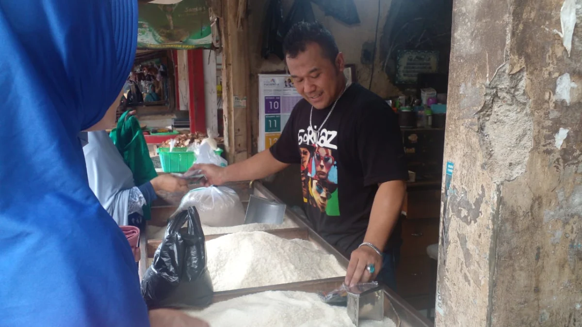 RESAH: Pemilik toko beras MM Pasar Sumedang, Dedi Hidayat saat sedang melayani pelanggan di tokonya, baru-baru ini.
