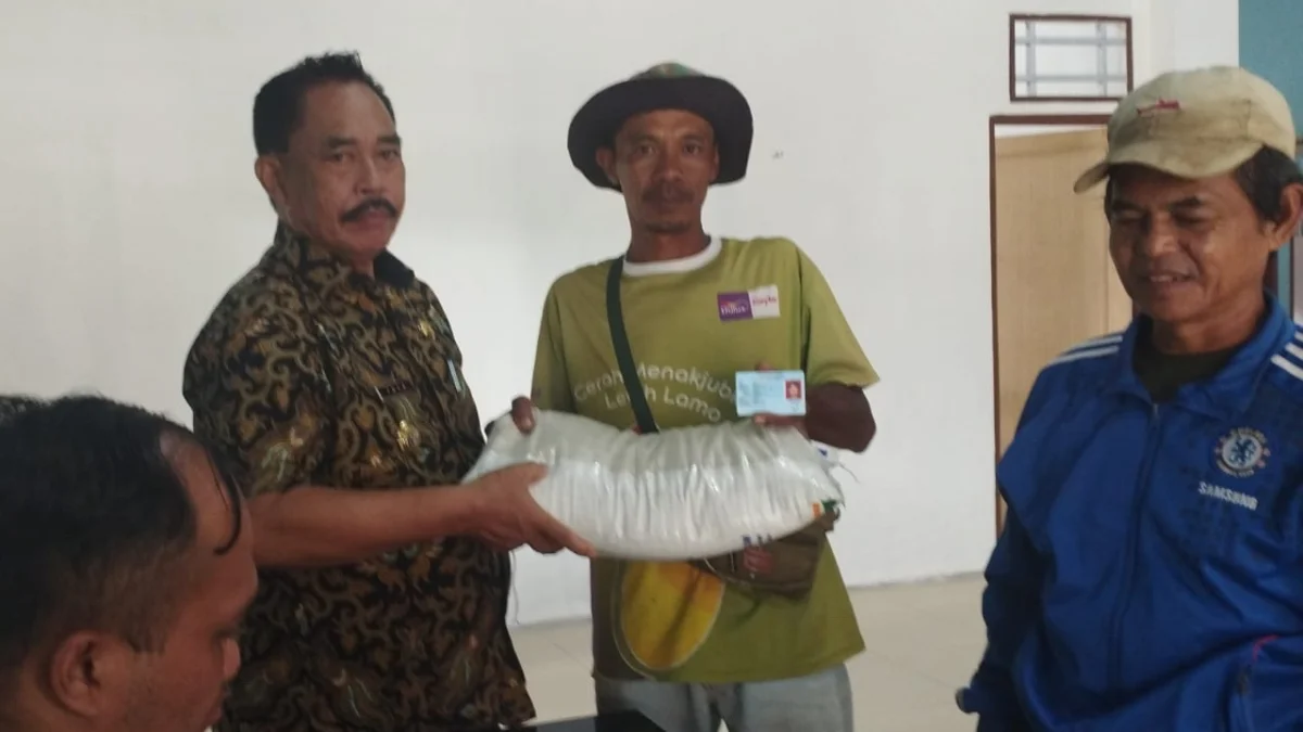 PEDULI: Kepala Desa Jatihurip, Tata saat memberikan bantuan beras 10 Kg kepada salah seorang warganya, baru - baru ini.