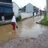 MENGGENANG: Salah satu siswa melintasi jalan yang tergenang banjir akibat luapan Sungai Cimande, di Desa Cihan