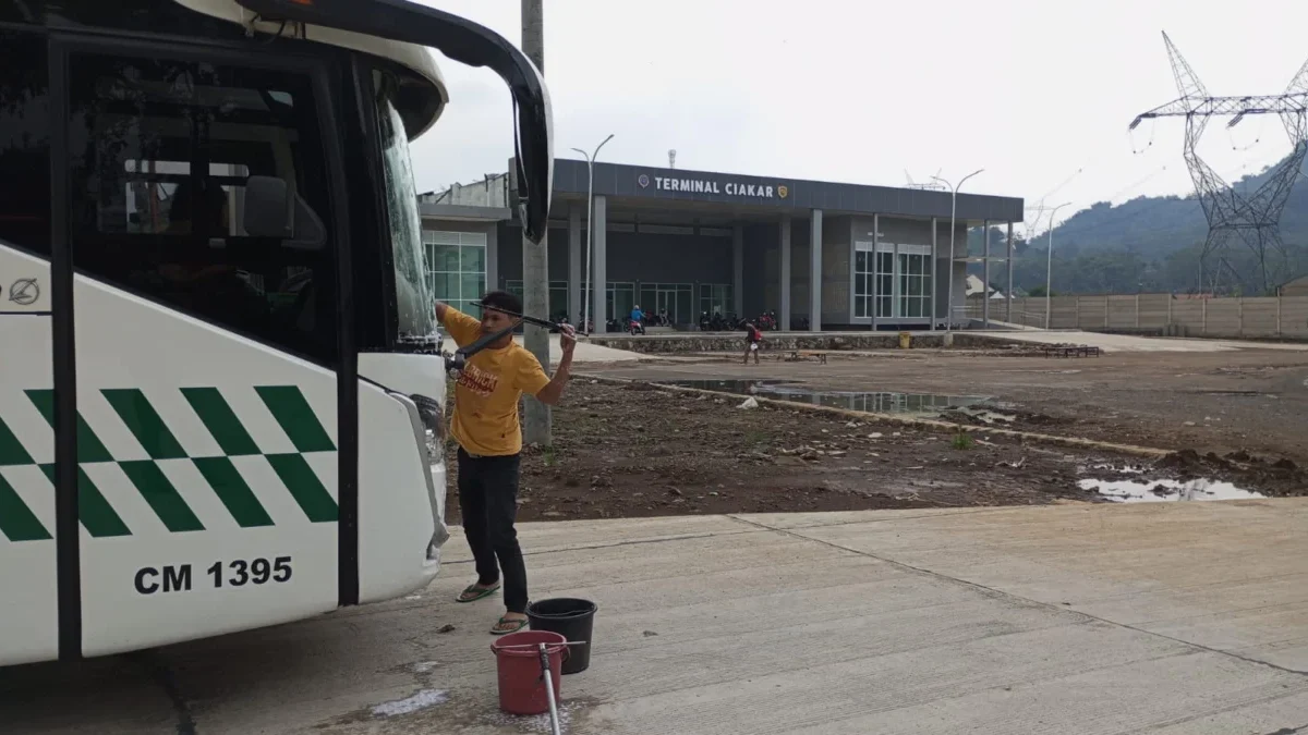 BERSIH-BERSIH : Salah seorang awak bis AKP jurusan Sumedang-Jakarta sedang membersihkan body kendaraan, di Ter