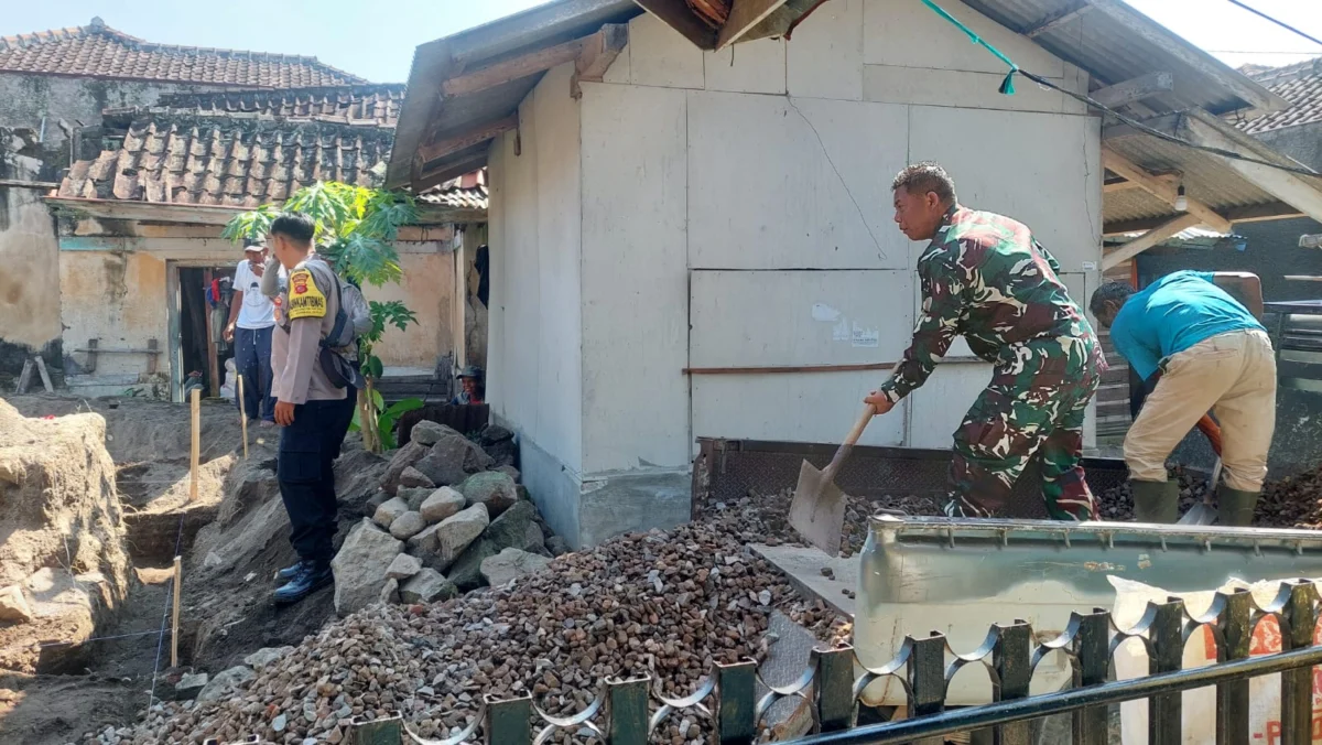 BERSINERGI: Anggota Babinsa Serka Zaenal Asikin saat membantu warga membangun Posyandu di Desa CIbeureum Weta,