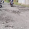 Pengendara sepeda motor menghindari jalan berlubang di Blok Kalijaga Mundu Pesisir.
