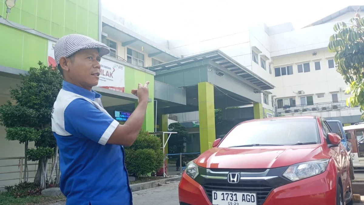 ATUR: Salah seorang petugas sedang mengatur kendaraan yang hendak parkir di halaman RSUD Sumedang, kemarin.