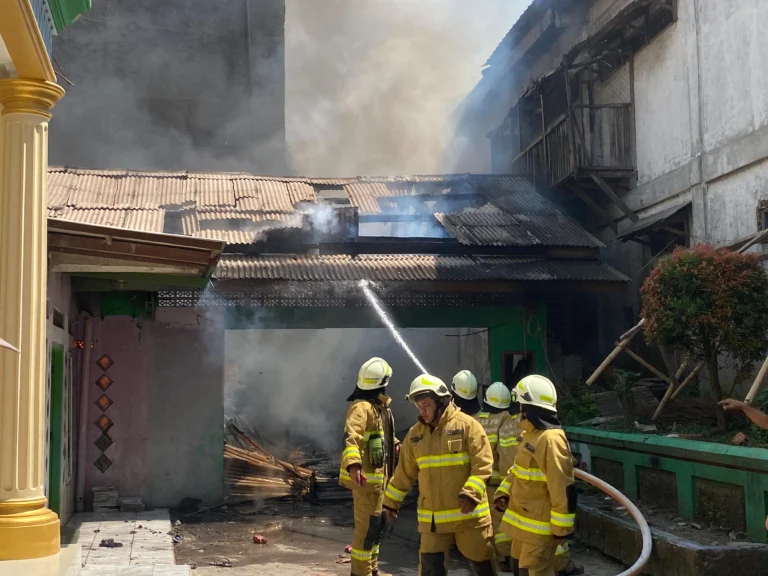 Para petugas pemadam kebakaran tengah memadamkan api yang melahap dua bangunan madrasah