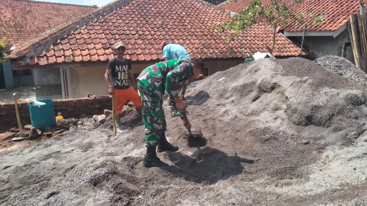 BERSINERGI: Babinsa Desa Cibugeul Serda Tedi Kurnaedi membantu warga membangun rumah, Selasa (10/9).